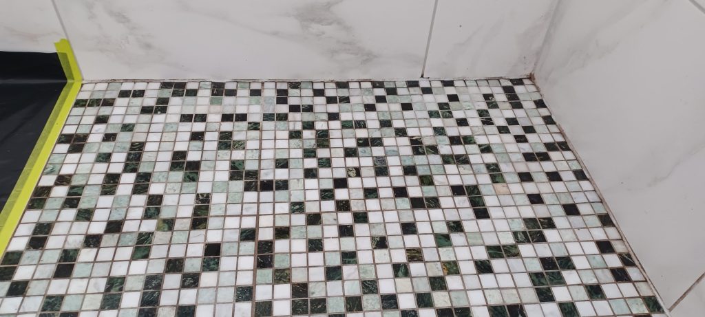 Old mouldy discoloured silicone peeling away from the join in a mosaic tiled shower in Edinburgh